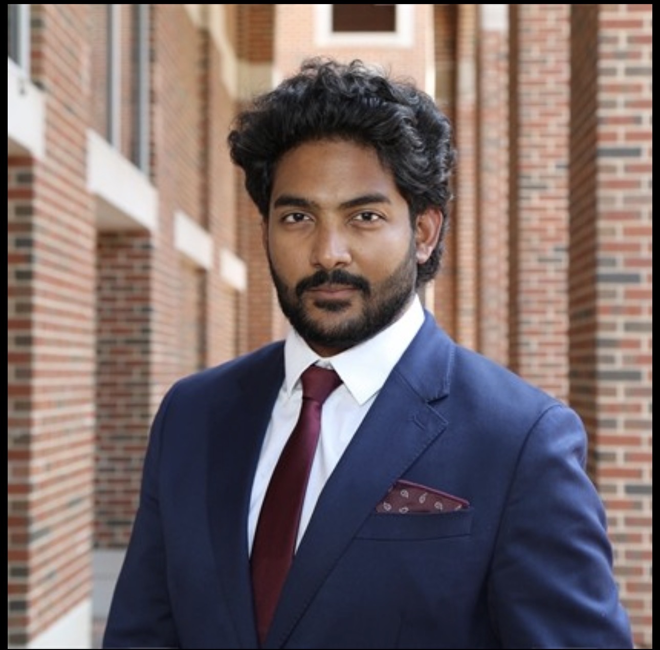 Teja Padala in a navy suit outside a brick building.